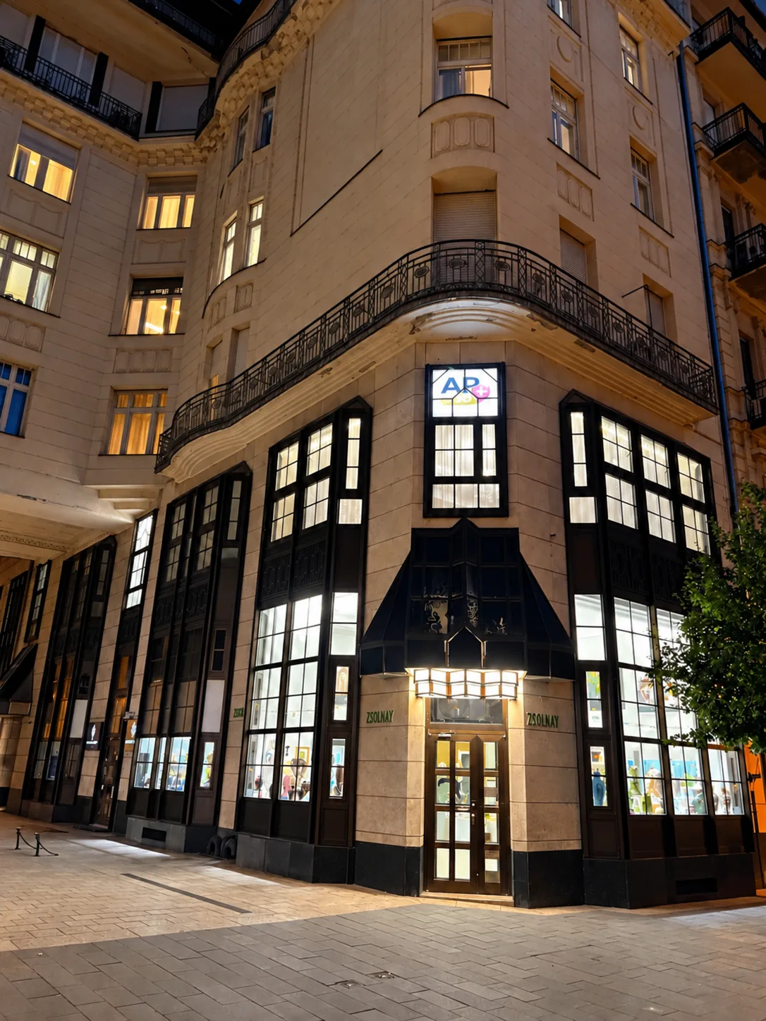 Az AP MED Center épülete éjszaka, a bejárattal és a kivilágított kirakatokkal